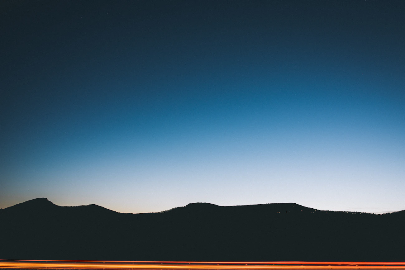 Silueta de montañas bajo un cielo azul al anochecer