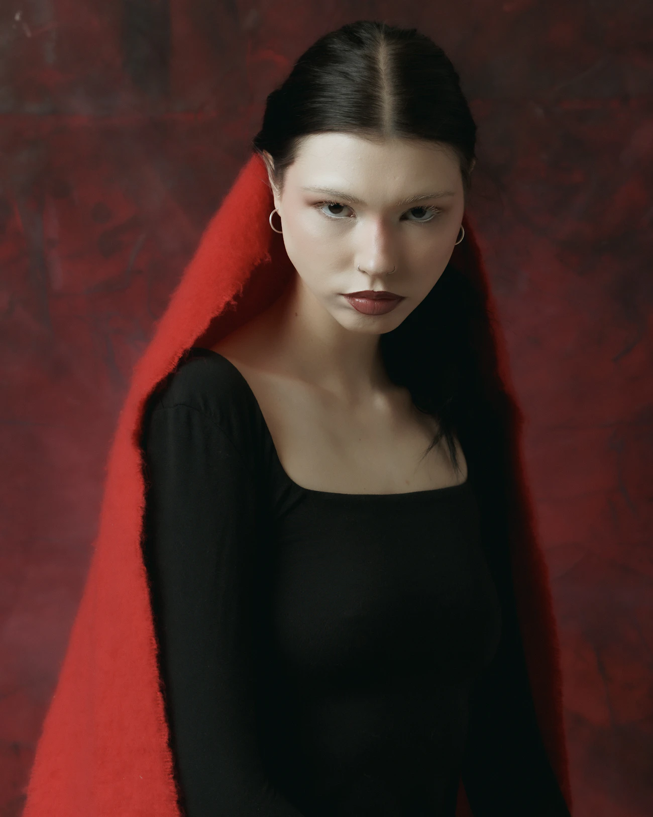 Retrato editorial de moda con tela roja y fondo de tono intenso